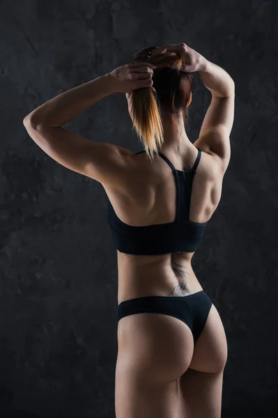 Menina fitness jovem se preparando para o treino isolado no fundo escuro — Fotografia de Stock