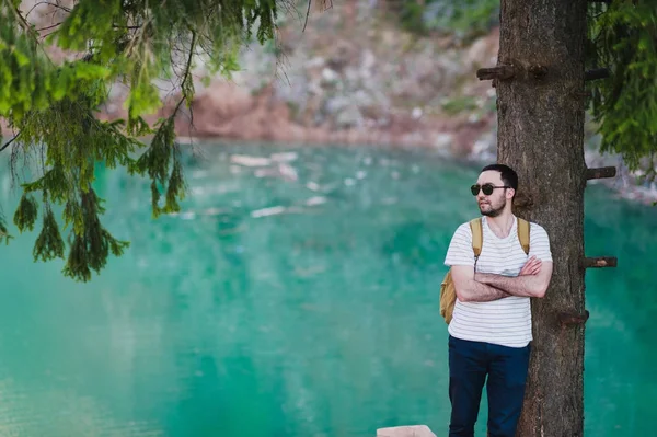 Barbudo modelo hombre posa junto a un lago de agua verde . — Foto de Stock