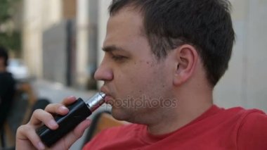 Ağır çekimde elektronik sigara kullanarak buharı exhaling bir adam portresi kapatın