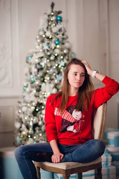 Joyeux jeune femme assise près de l'arbre de Noël. — Photo