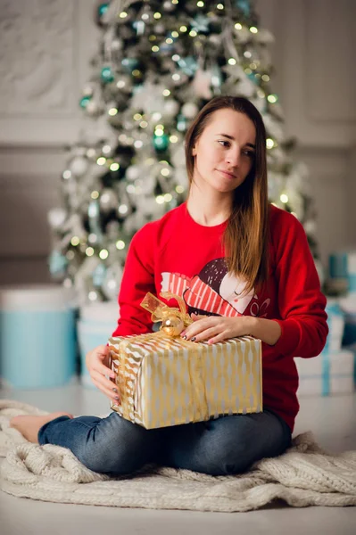 Portrait de belle femme avec cadeau assis près de l'arbre de Noël à la maison — Photo
