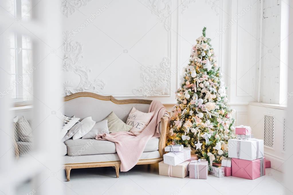 Classic Christmas light interior in white and pink tones with a couch, tree and molding in the Baroque style and renaissance.