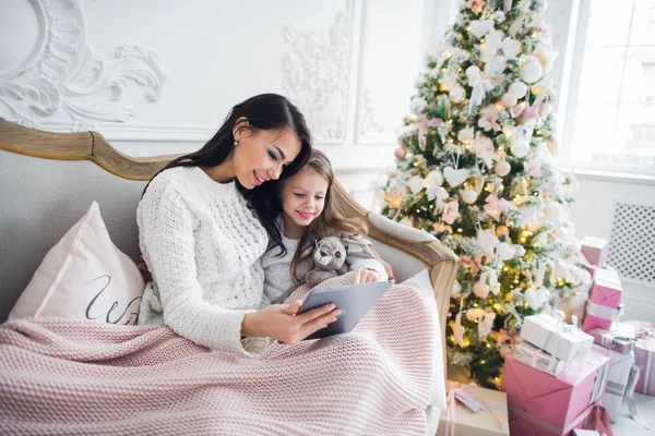 Hermosa joven y su hija con la tableta en Navidad. Primer plano. —  Fotos de Stock