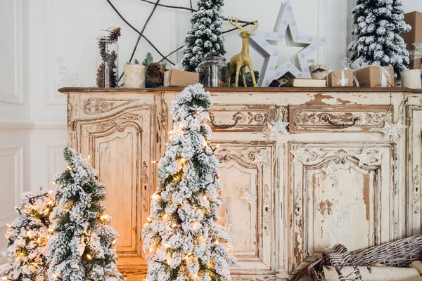 Julgran på trä byrå byrå byrå låda i vit interiör, dekorerad med konstgjorda blommor, girlanger och leksaker — Stockfoto