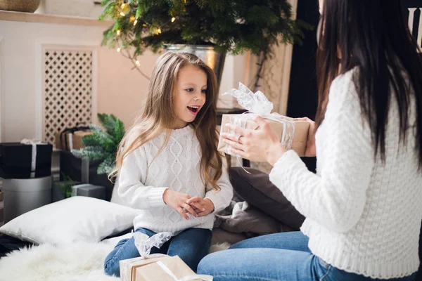 Joyeux Noël et Joyeuses Fêtes. Joyeux maman et sa fille mignonne fille ouvrant un cadeau de Noël. Parent et petit enfant s'amusent près de l'arbre de Noël à l'intérieur — Photo