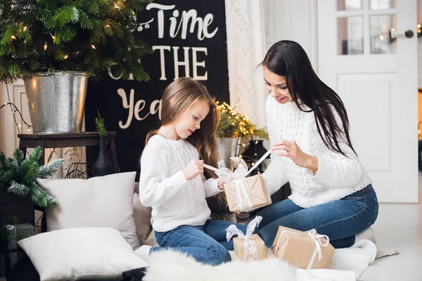 Joyeux Noël et Joyeuses Fêtes. Joyeux maman et sa fille mignonne fille ouvrant un cadeau de Noël. Parent et petit enfant s'amusent près de l'arbre de Noël à l'intérieur — Photo