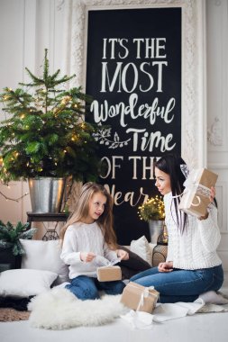 Genç şık güzel kadın elbiseli kızı evde elleri ile oynamanın xmas üzerinde kutladı. Küçük kız tatil tatlı annesi hediyeler için teşekkürler