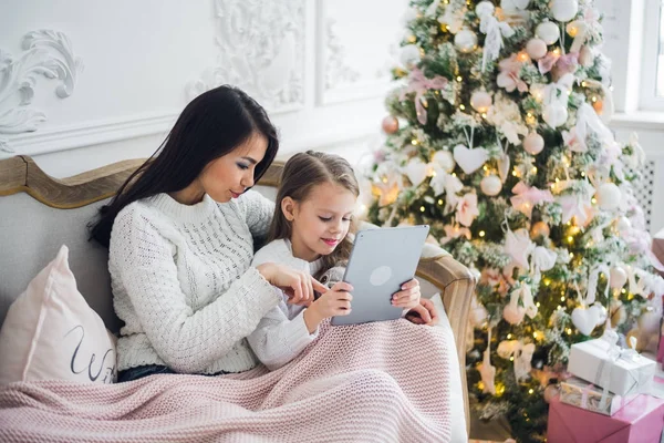 Hermosa joven y su hija con la tableta en Navidad. Primer plano. —  Fotos de Stock