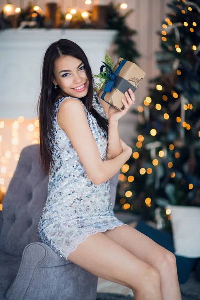 若いです幸せな美しい女性でギフトボックス近くに座っているクリスマスツリーの家の部屋に — ストック写真