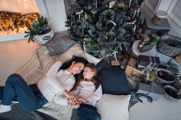 Hermosa familia feliz madre e hija con regalos alrededor del árbol de Navidad están en el suelo juntos en casa —  Fotos de Stock