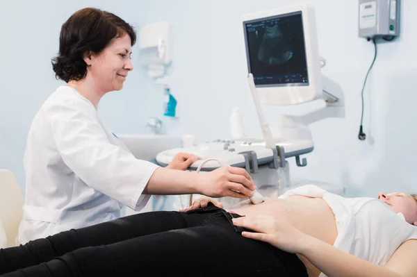 Gravid kvinna och läkare händer med ultraljudsutrustning — Stockfoto