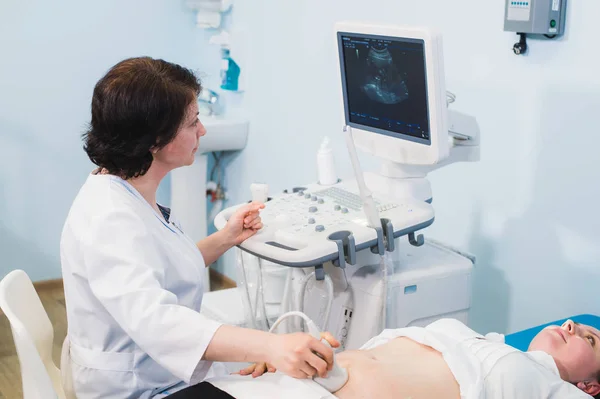 Беременная женщина и врач руки с ультразвуковым оборудованием — стоковое фото