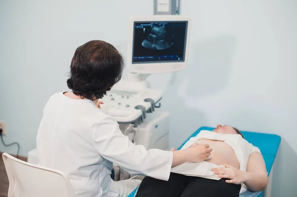 Lekarz za pomocą USG i badania przesiewowe żołądka w ciąży kobiety. — Zdjęcie stockowe