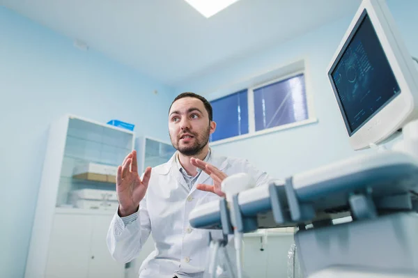 年轻的男医生向孕妇在医院解释超声扫描 — 图库照片