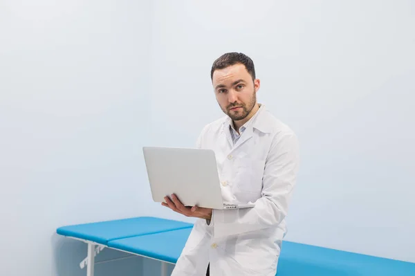 Médico exitoso mental de pie en su oficina y el uso de la computadora portátil para su trabajo — Foto de Stock