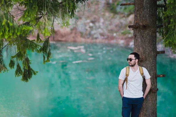 Модель бородатого мужчины позирует рядом с озером зеленой воды . — стоковое фото