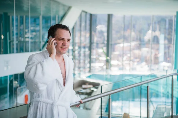 El hombre utiliza el teléfono celular en el spa del hotel de lujo en el cercano a la piscina —  Fotos de Stock