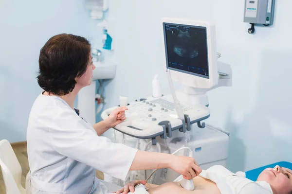 Беременная женщина и врач руки с ультразвуковым оборудованием — стоковое фото