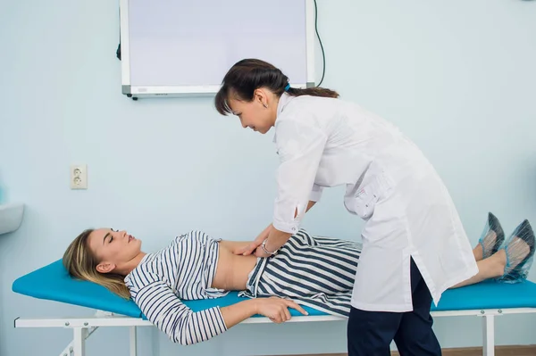 Läkare kontrollera magen av en av hennes patienter — Stockfoto