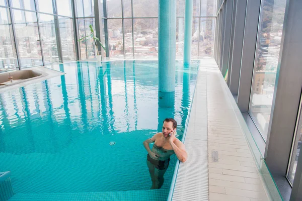 Homem falando no celular dentro da piscina no hotel de luxo — Fotografia de Stock