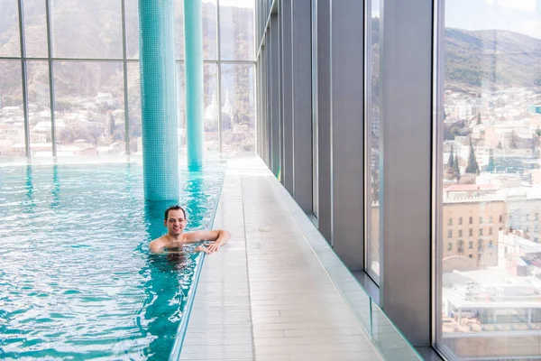 Hombre guapo relajándose en una piscina cubierta — Foto de Stock