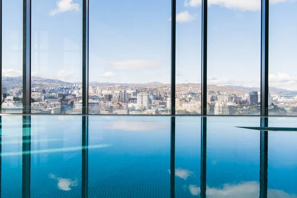 Interior contemporâneo com piscina e vista para a cidade. Grande superfície de água — Fotografia de Stock