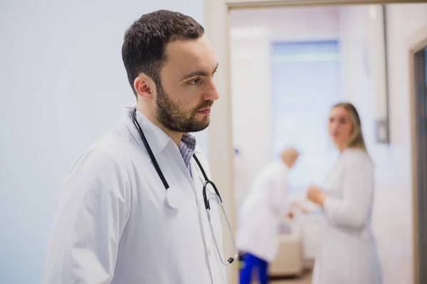 Vista lateral del joven médico reflexivo en uniforme médico escuchando al paciente — Foto de Stock