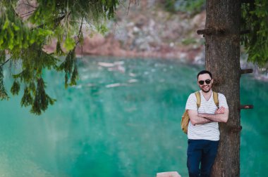 Sakallı adam modeli pozlar yanında yeşil bir göl su.