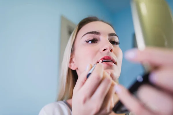 Mujer joven aplicando lápiz labial mirando al espejo — Foto de Stock