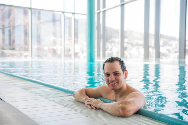 Hombre guapo relajándose en una piscina cubierta — Foto de Stock
