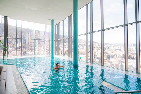 Homem bonito relaxando em uma piscina interior — Fotografia de Stock