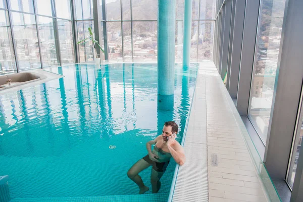 Homem falando no celular dentro da piscina no hotel de luxo — Fotografia de Stock