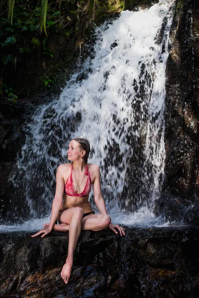 Hipster girl in swimwear posing in jungle forest sitting on a river waterfall. Alone unity with nature. Keep clam in travel — Stock Photo, Image