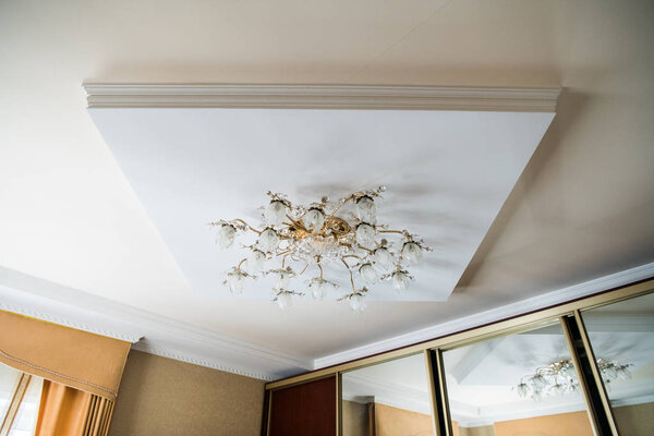 vintage chandelier hanging under white ceiling with stucco moldings