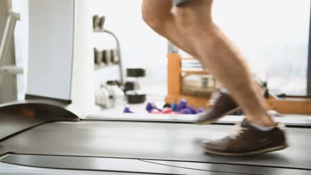 Sport, fitness, technology and people concept - close up of male legs running on treadmill in gym — Stock Video