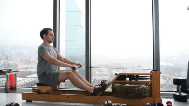 Man som arbetar på roddmaskin på gym — Stockvideo