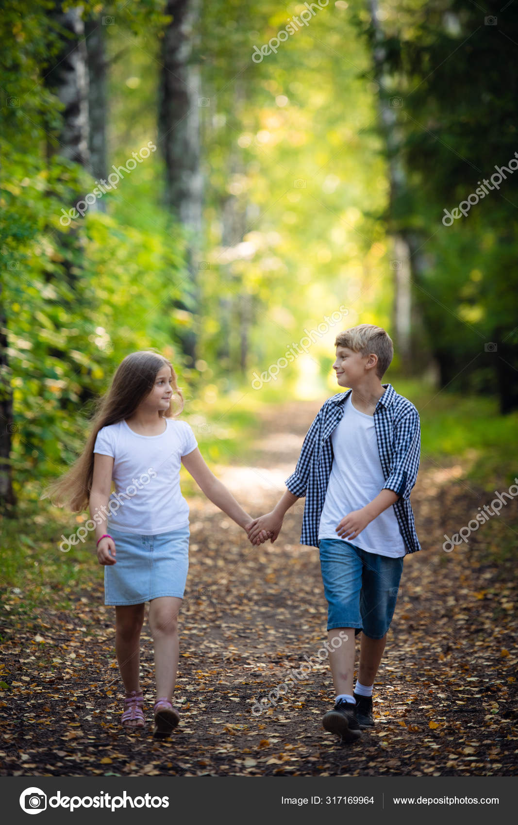 First love. Little boy and girl holding hands and smiling while walking  outdoors in park — Stock Photo © romankosolapov #317169964, image size:1067x1700