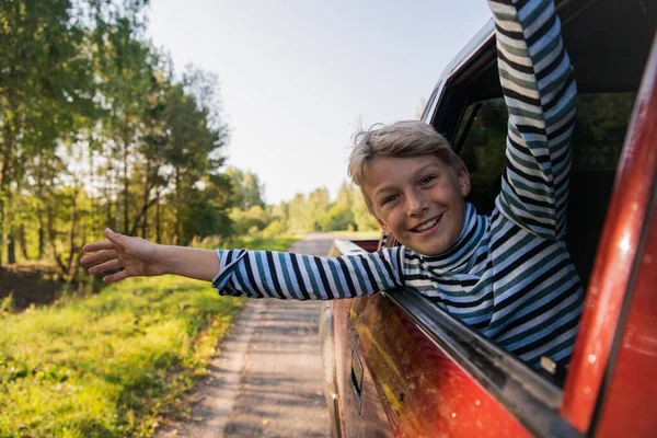 Un niño feliz viajando en coche. Salió por la ventana —  Fotos de Stock