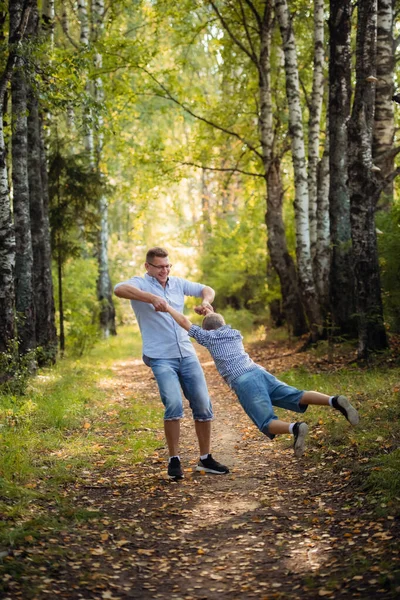 Happy father playing with his son picking him up in his arms. The boy imagines he flies like a plane