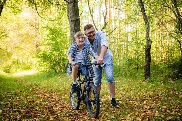 Père enseignant à son fils à faire du vélo dans un parc d'automne — Photo