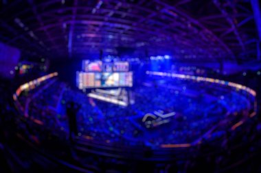 Esport etkinliğinin arka planında bulanıklık var. Büyük bir stadyumdaki bilgisayar oyunları turnuvasının büyük bir sahnesi aydınlandı. Tribünler video oyunu hayranlarıyla dolu..