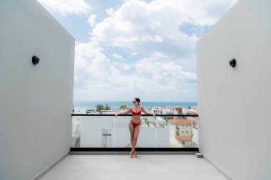 Arka planda güzel bir şehir ve okyanus manzaralı çatı havuzunun yanında mutlu bir kadın.