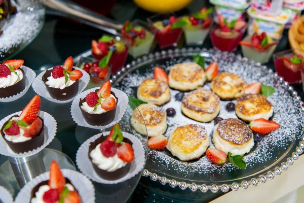 Pasteles de queso con crema agria, menta, fresas en un desayuno buffet —  Fotos de Stock