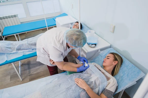 Enfermera profesional haciendo una inyección a una mujer acostada en la mesa de operaciones en el hospital preparando el concepto de cirugía médica anestésica . — Foto de Stock