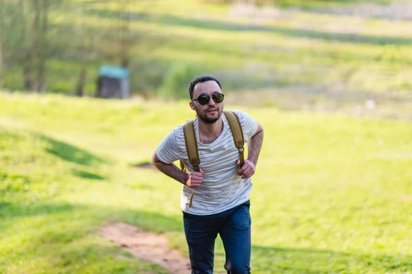 Senderismo retrato de hombre con mochila caminando en la naturaleza. Hombre caucásico sonriendo feliz con el bosque en el fondo durante el viaje de verano — Foto de Stock