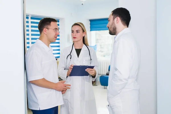 Vista de ángulo alto de tres médicos con batas blancas conversando en la sala del hospital — Foto de Stock