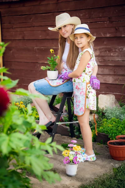 Femme et fille, mère et fille, jardinage ensemble plantant des fleurs dans le jardin. Regardant la caméra — Photo