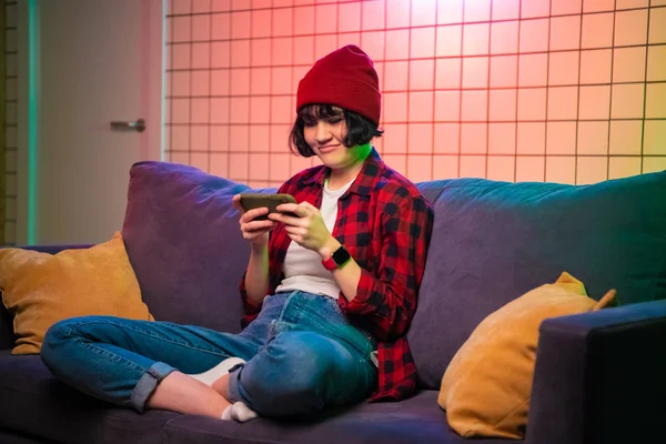 Chica adolescente sosteniendo un teléfono inteligente mientras juega juegos de disparos en línea . — Foto de Stock