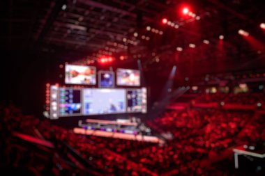 Esport etkinliğinin arka planında bulanıklık var. Büyük bir stadyumdaki bilgisayar oyunları turnuvasının büyük bir sahnesi aydınlandı. Tribünler video oyunu hayranlarıyla dolu..