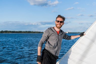 Young adult fisherman staying with happy smile on yacht by the sea